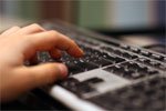 Close-up of fingers typing on a computer keyboard.