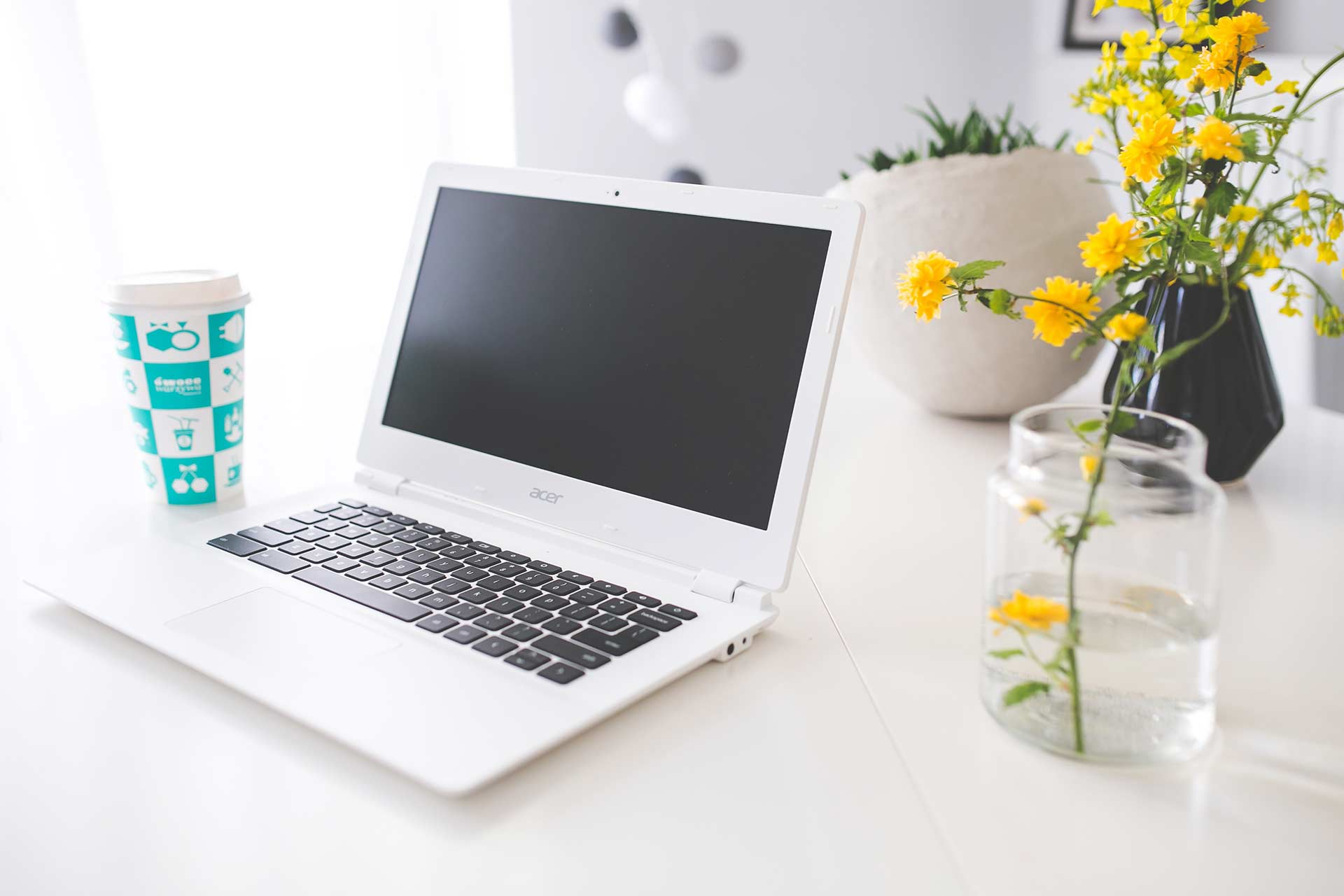 laptop next to yellow flower arrangement