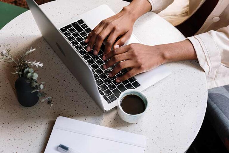 Person using laptop with coffee at desk.