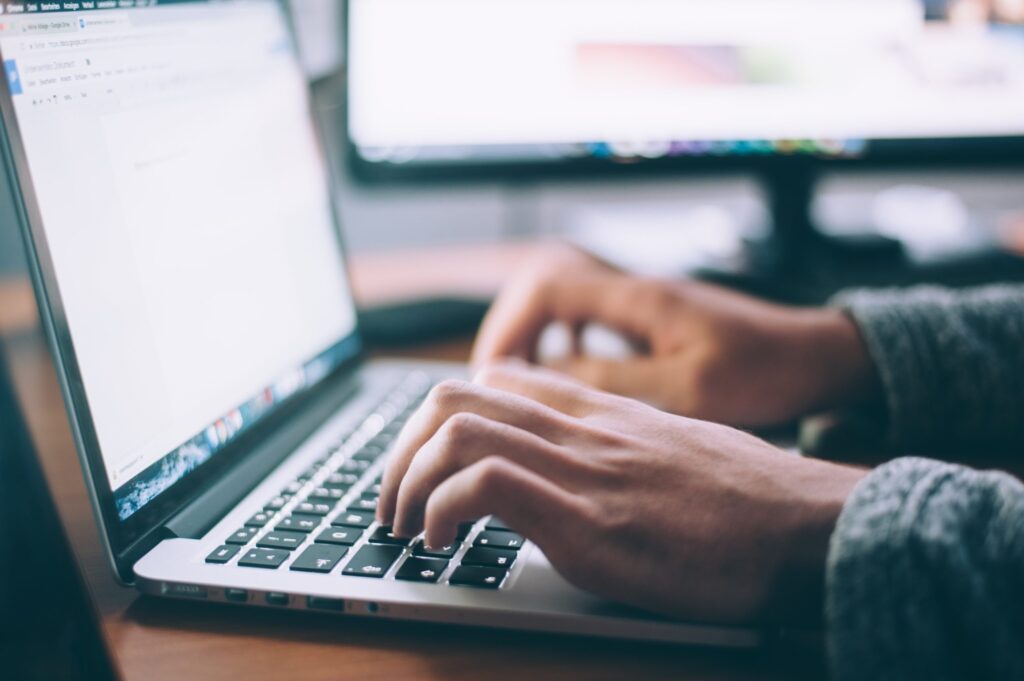 Person typing on laptop in cozy sweater.