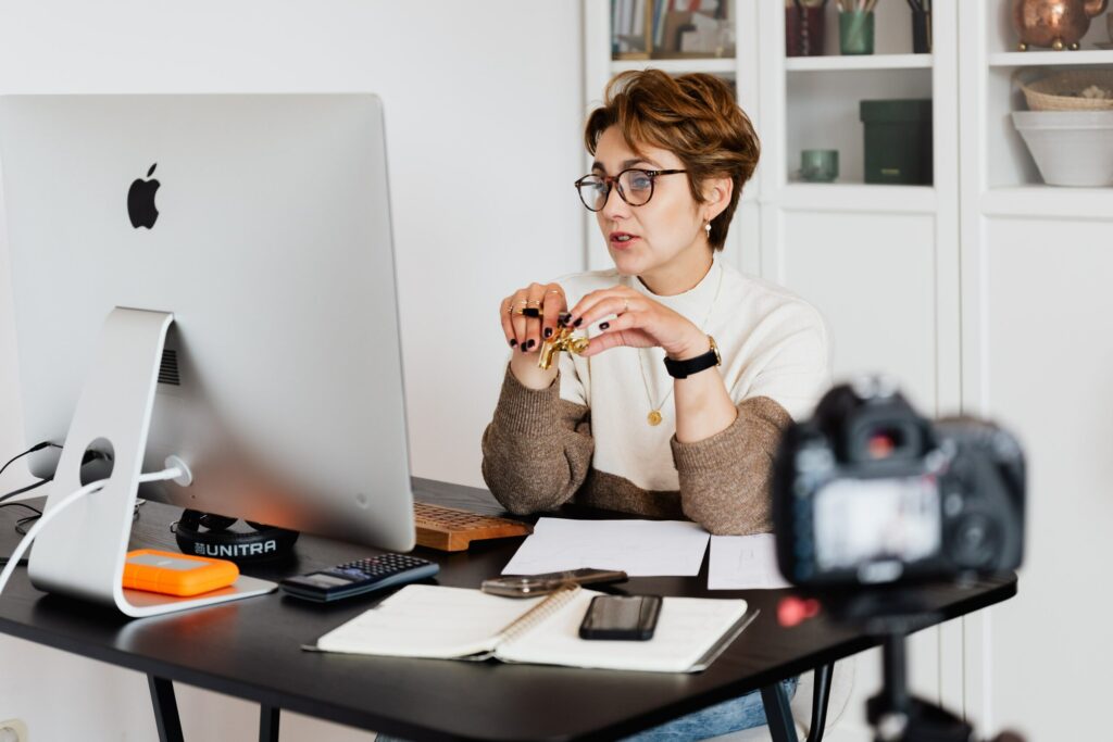 Woman working on computer while recording a video blog.