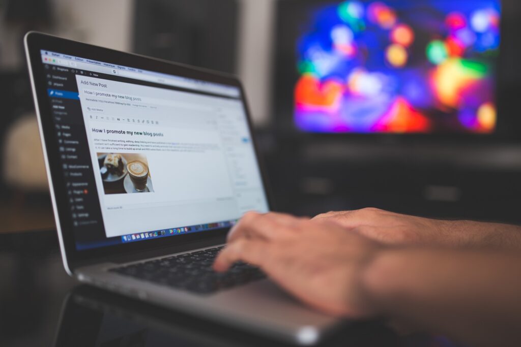 Person blogging on laptop with coffee, colorful background.