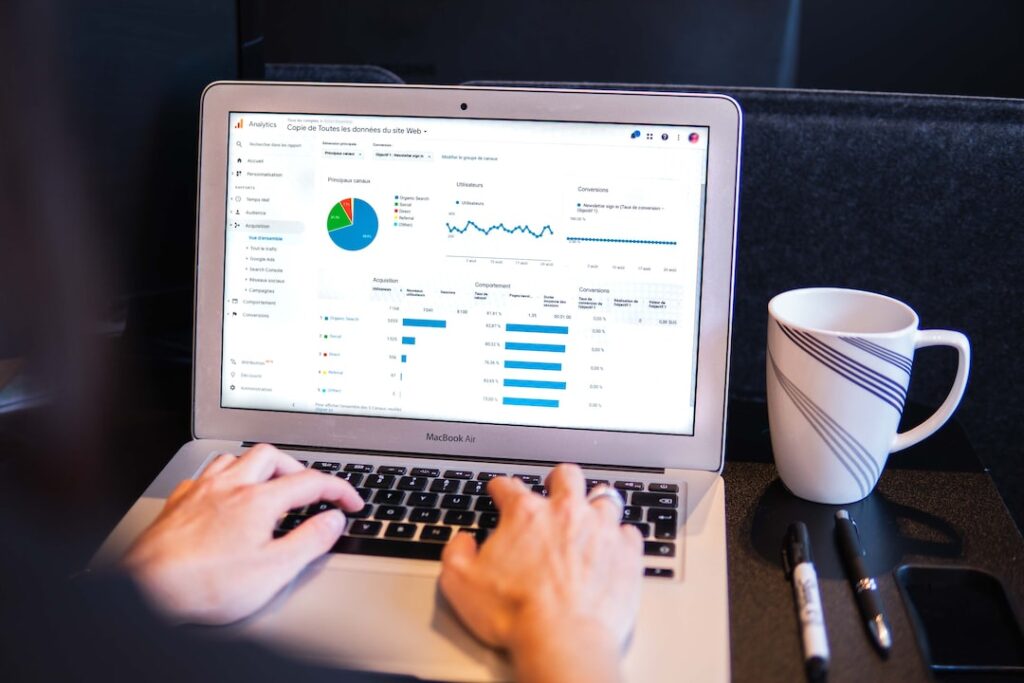 Person analyzing web analytics on laptop with coffee.