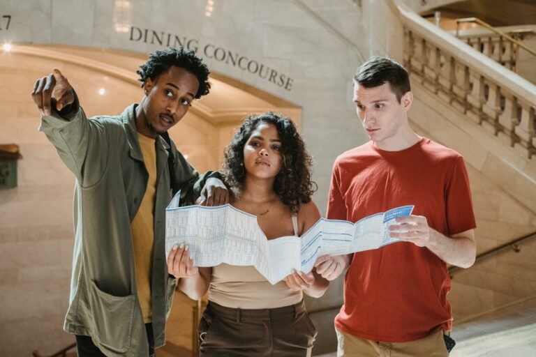 Three friends consulting map indoors, pointing and discussing.