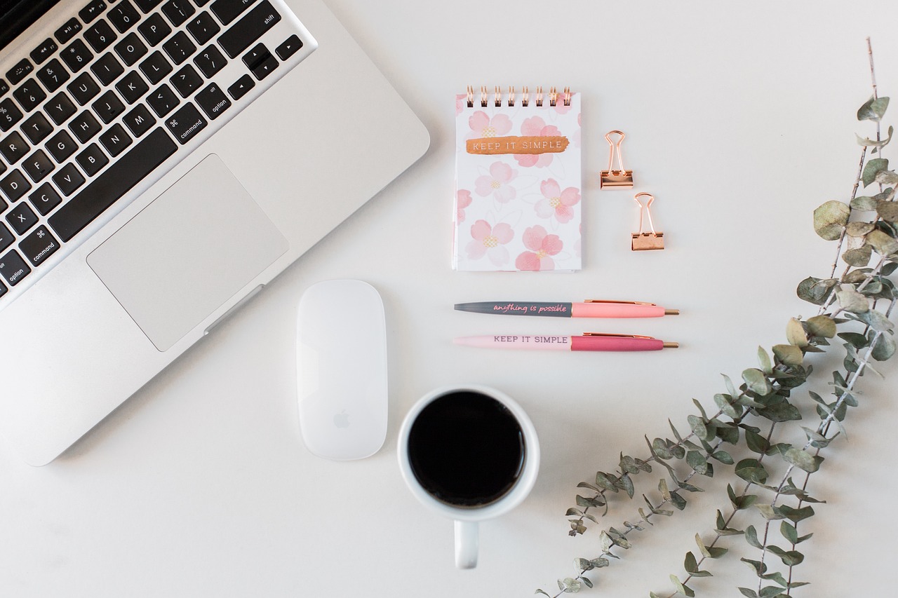 Minimalist workspace with laptop, notepad, pens, and coffee.