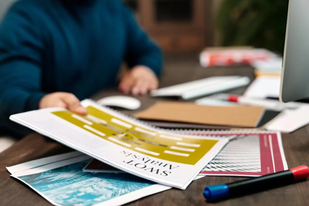 Person organizing creative project plans on desk