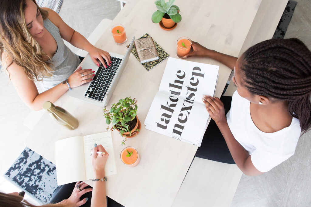 Three women working at a table with laptops.