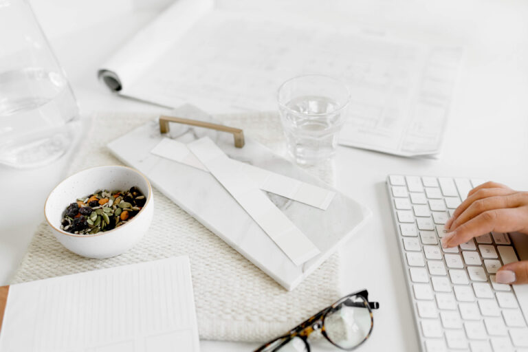 Person typing near healthy snack and office items.