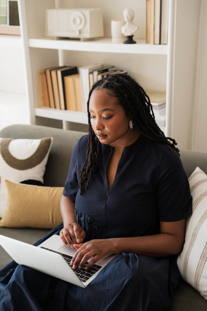 Person typing on laptop in cozy living room.