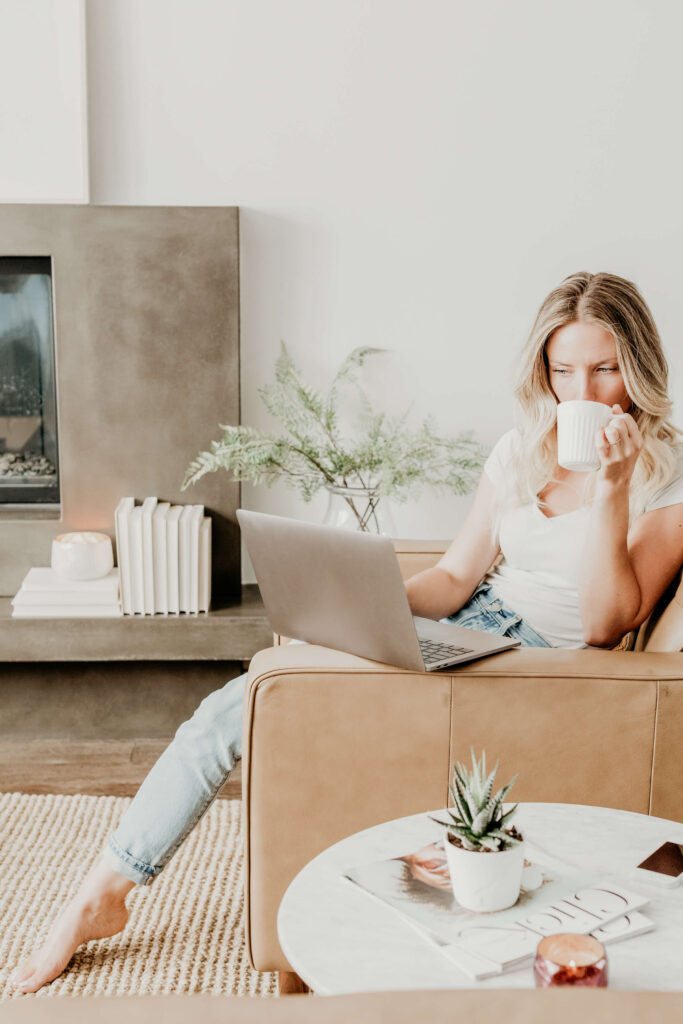 Woman drinking coffee and using laptop at home.