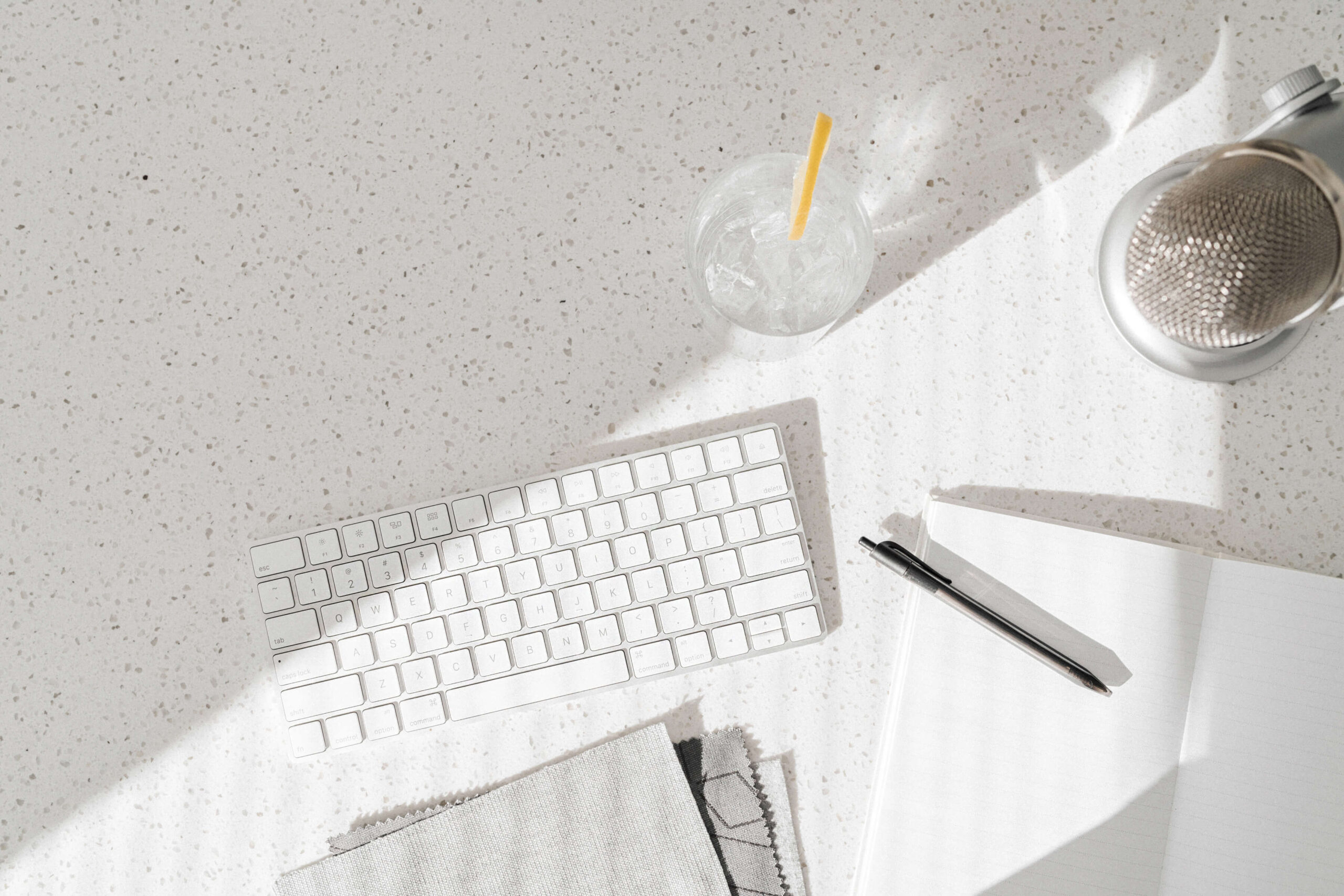 Workspace with keyboard, microphone, notebook, and drink.