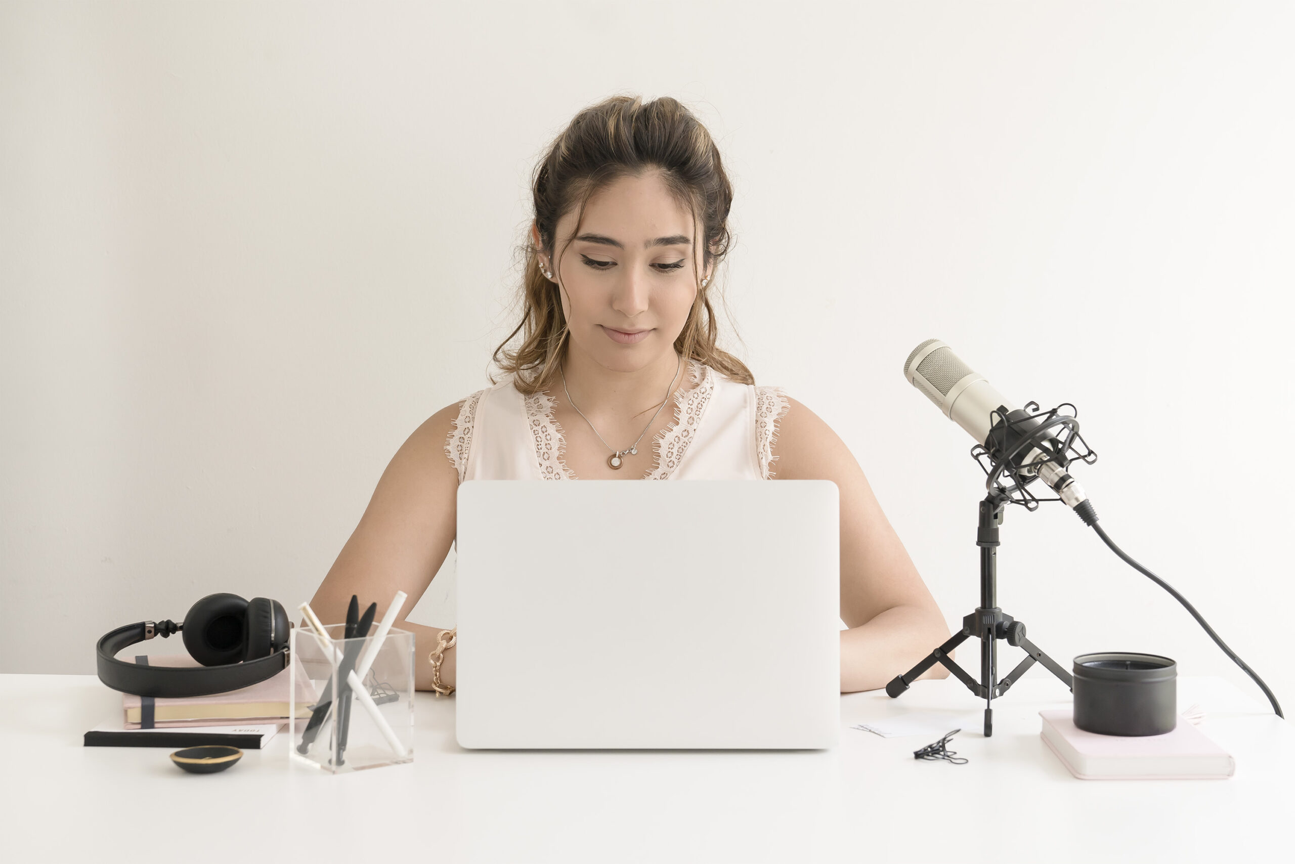 Woman podcasting with laptop and microphone setup.
