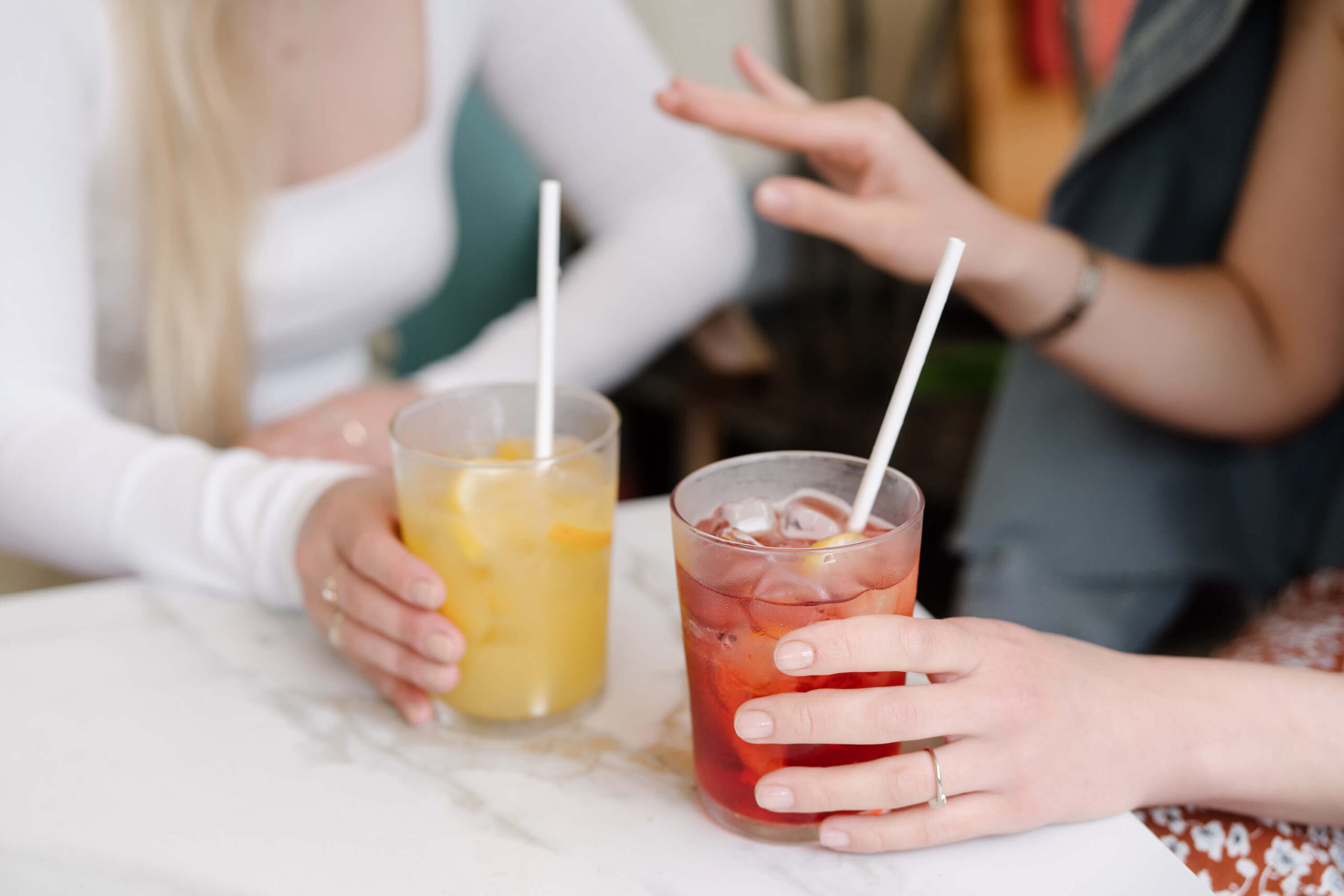 Two people holding lemonade and iced tea drinks.