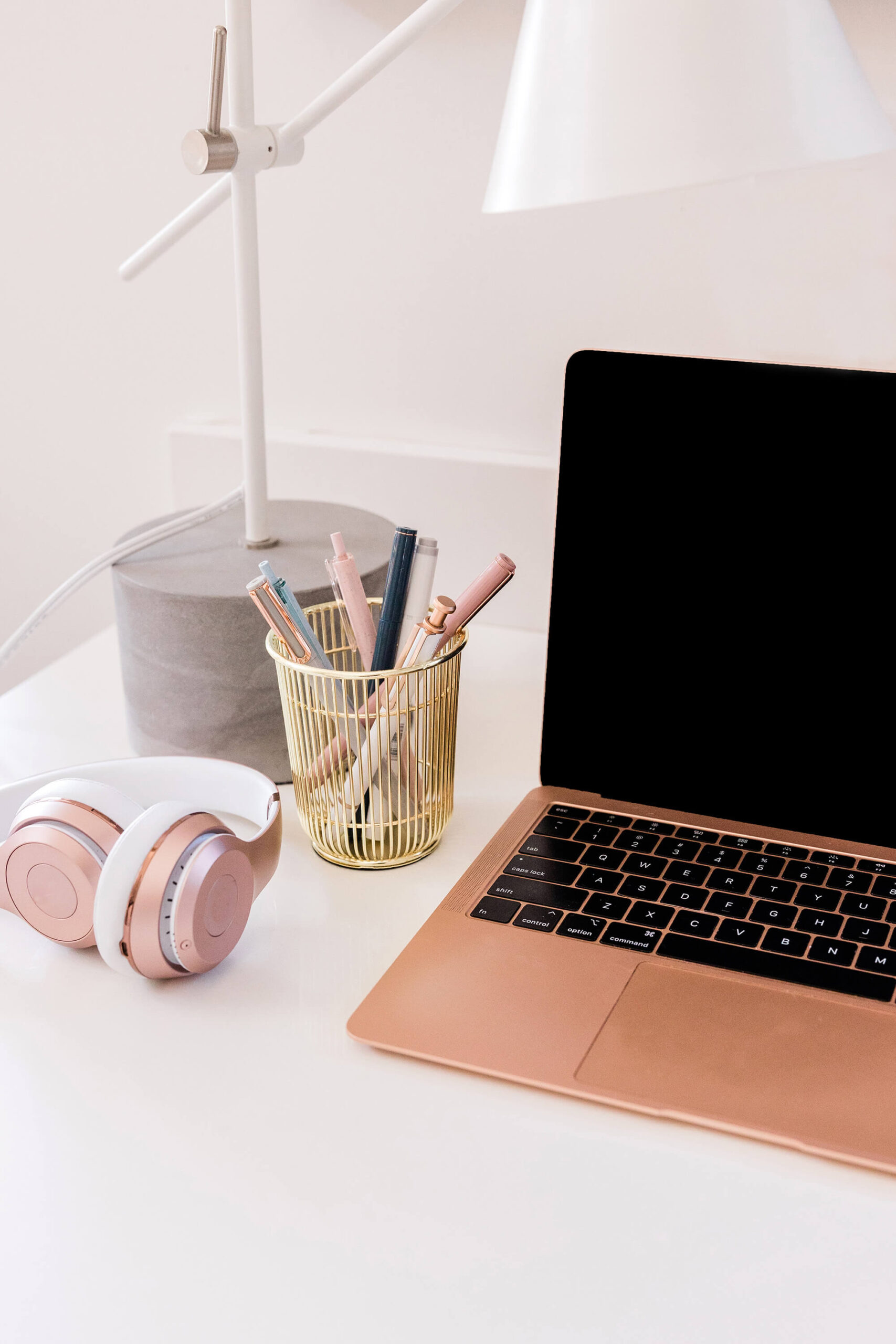Desk with laptop, pens, and headphones.