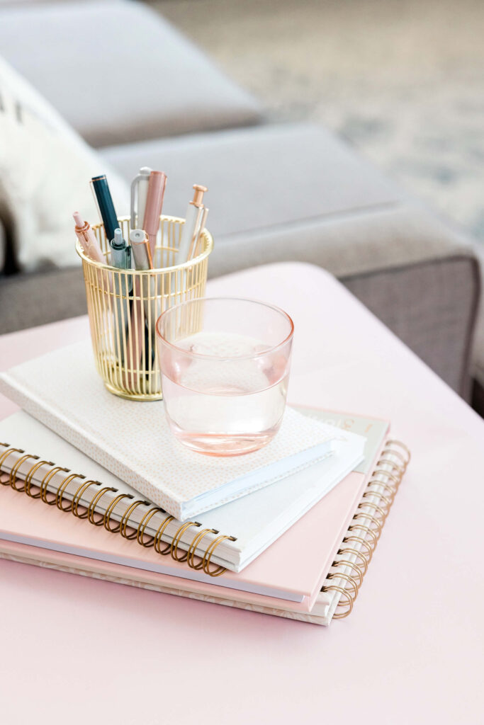 Desk with notebooks, pens, and glass of water.