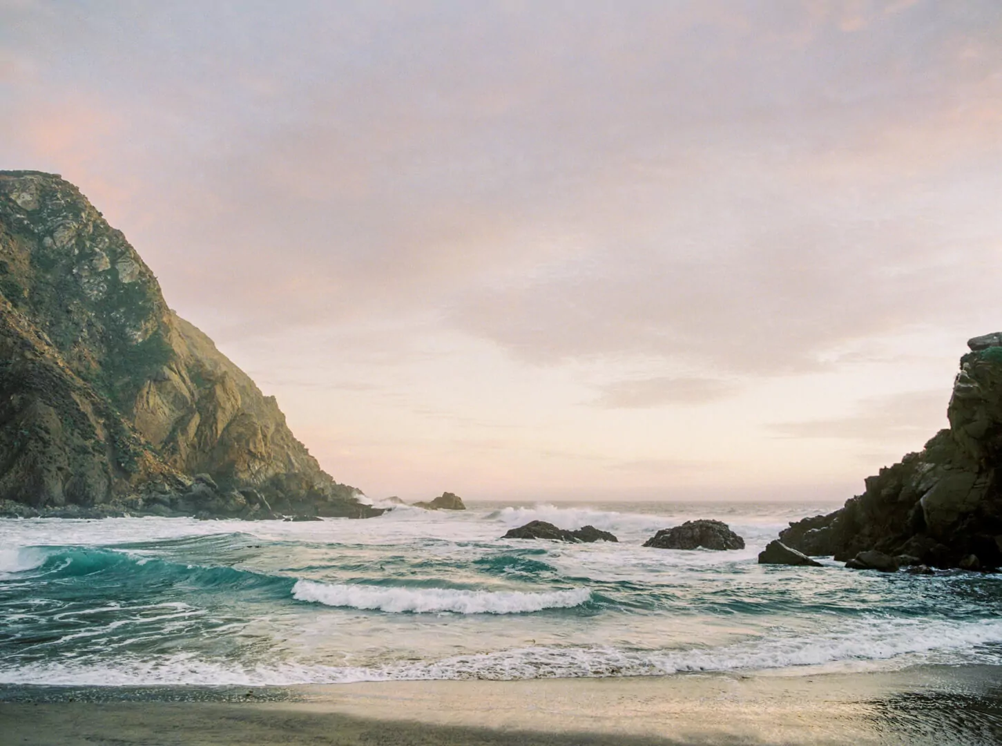 Rocky coastline at sunset with waves crashing
