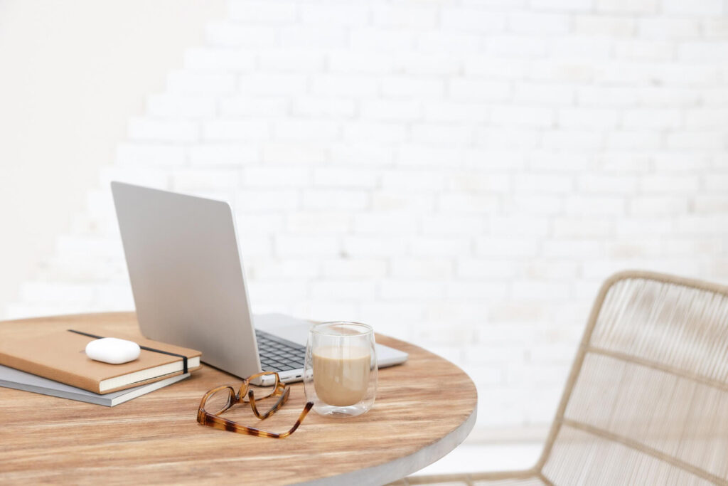 Laptop, books, glasses, coffee on wooden table