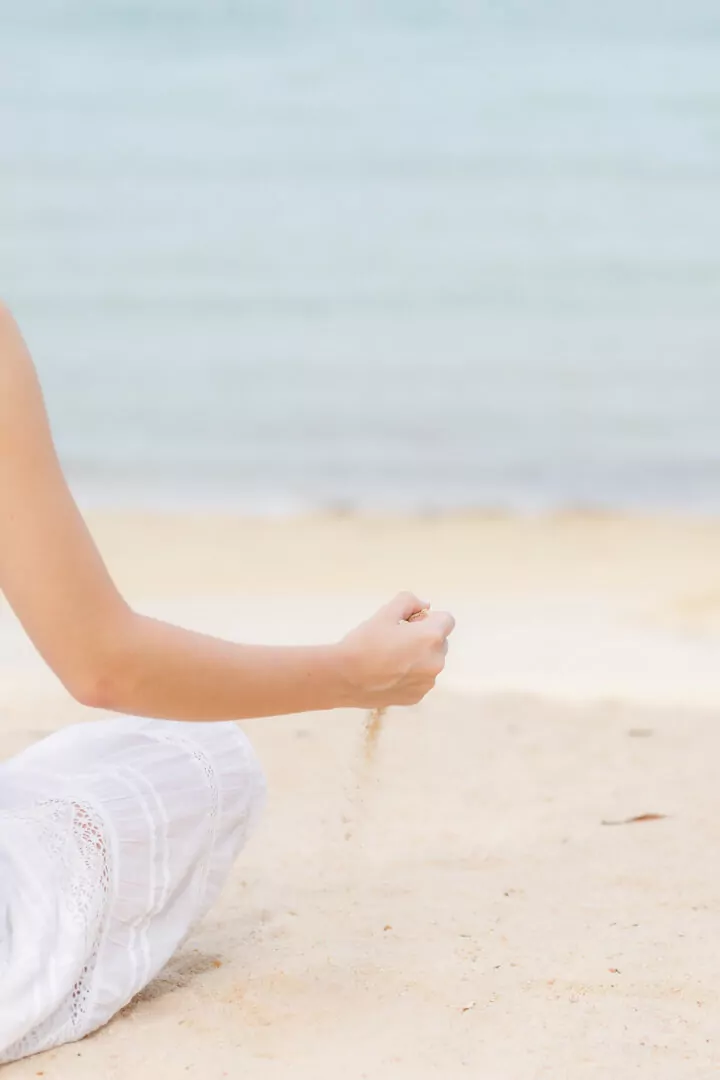 Hand letting sand fall on beach