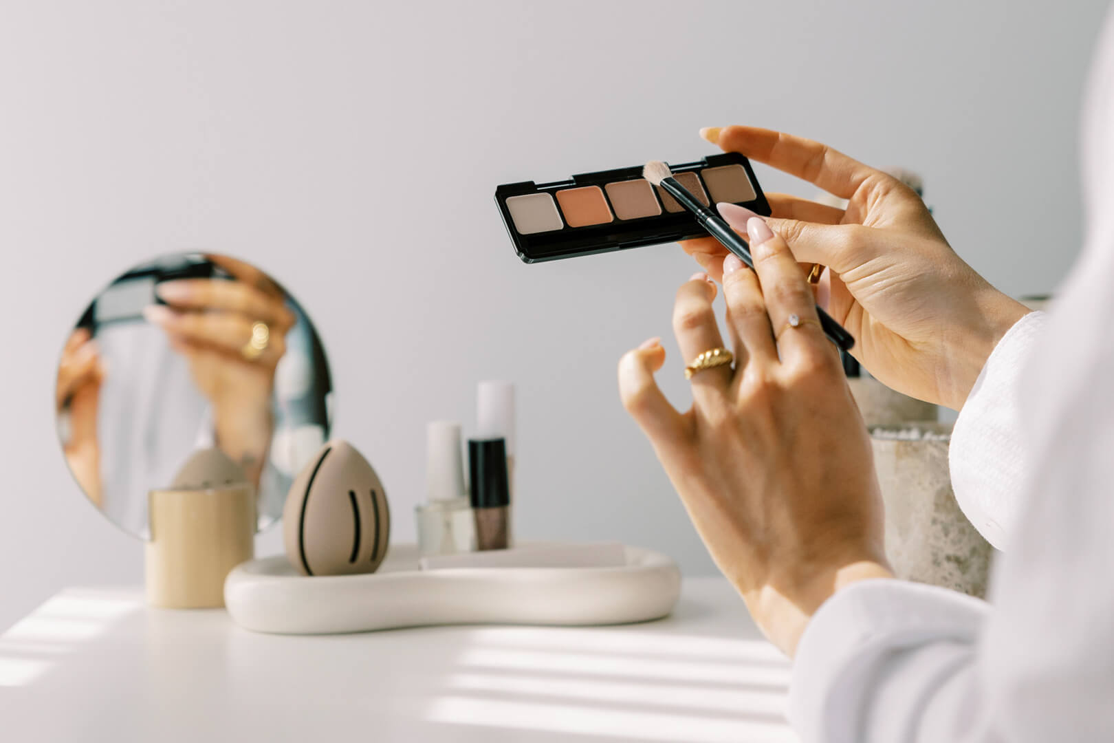 Applying eyeshadow with a brush near a mirror.