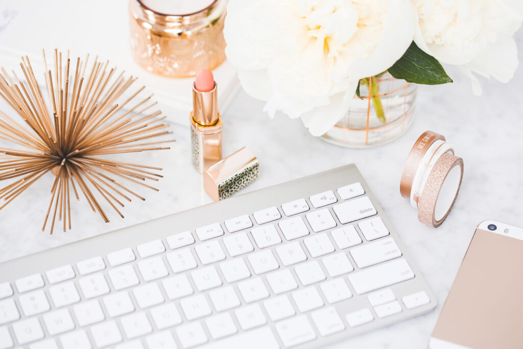 White keyboard with pink accessories and flowers.