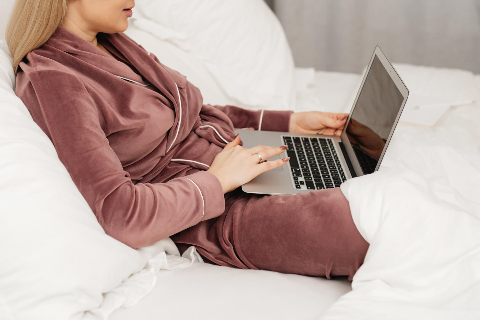 Person in robe using laptop on bed