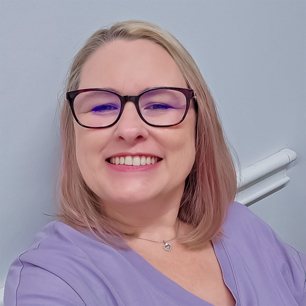 Person smiling in lavender shirt and glasses