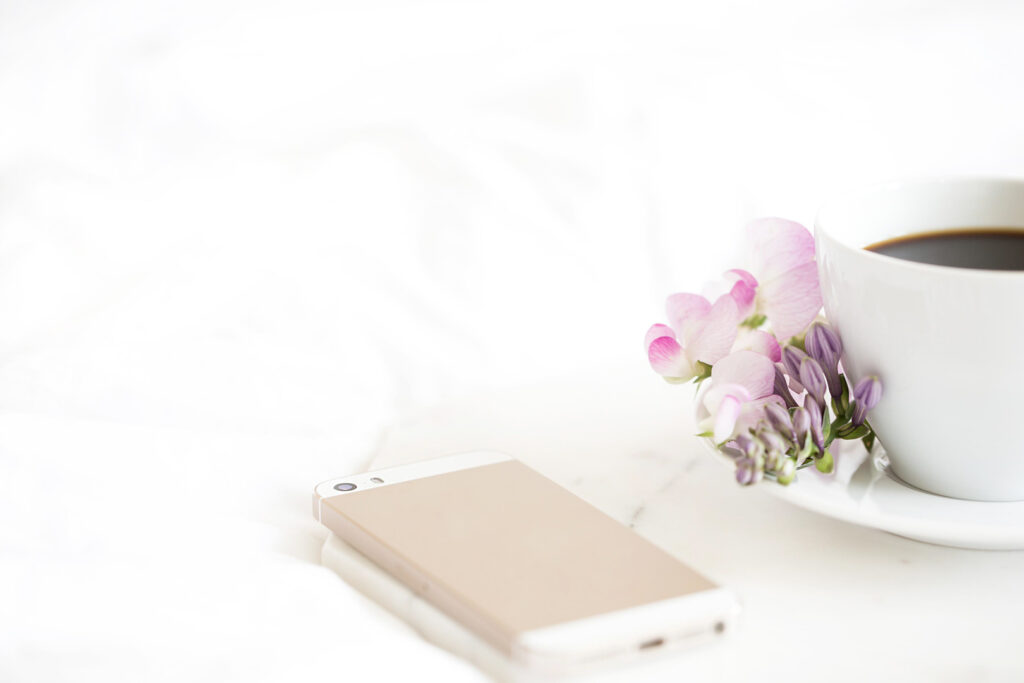 Smartphone, flowers, coffee cup on white background.