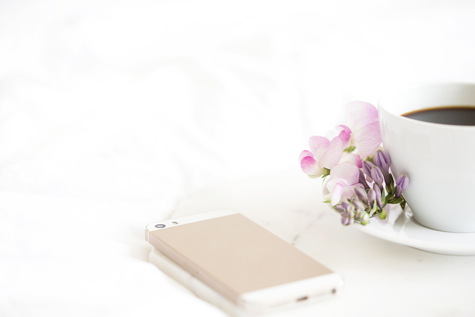 Smartphone, flowers, coffee cup on white background.