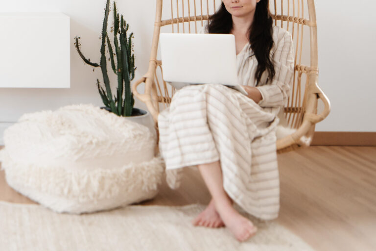 Woman using laptop in cozy room with plant.