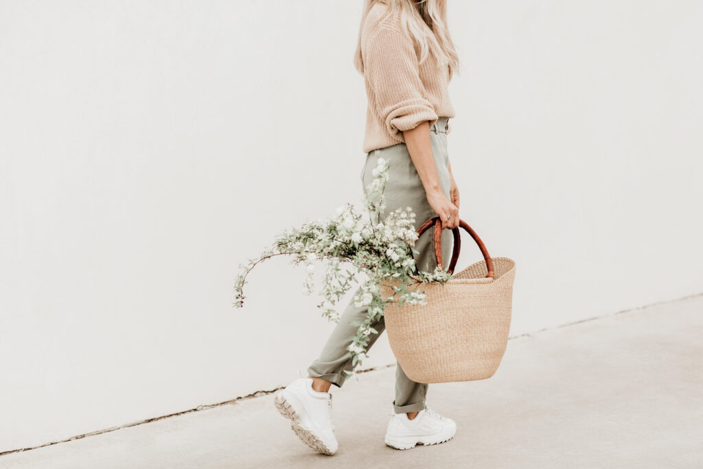 Person carrying basket with flowers walking.