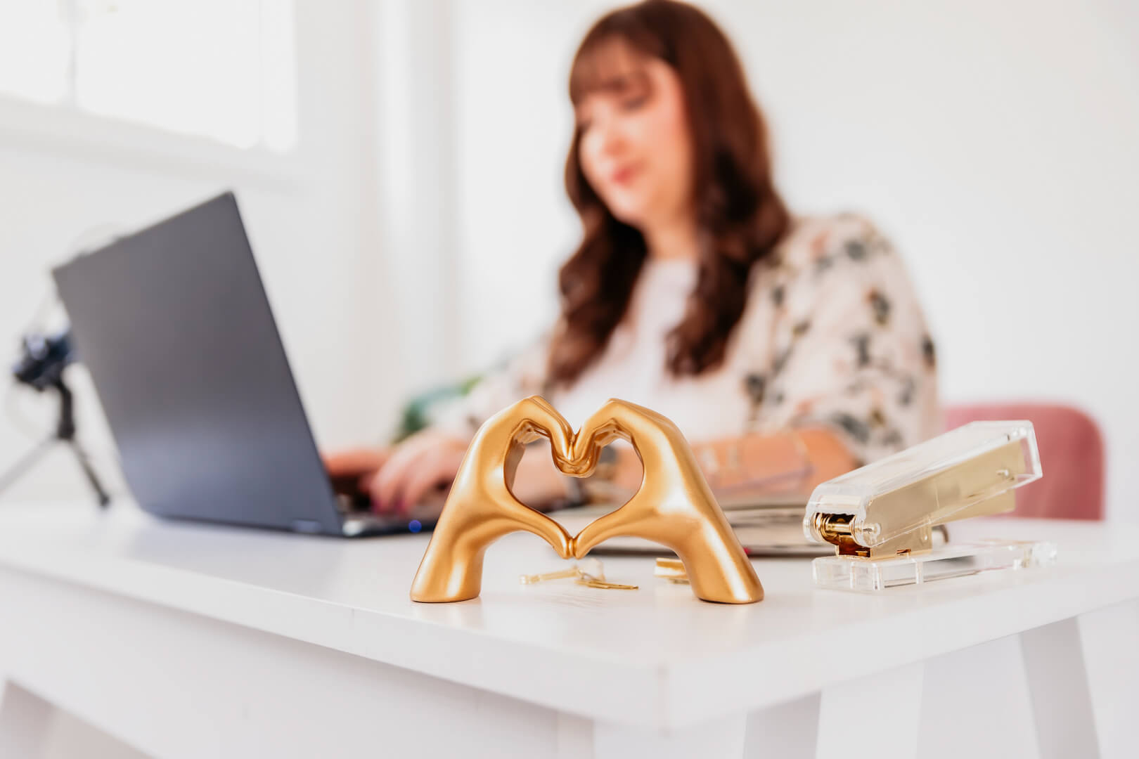 Woman working on laptop with decorative gold hands.