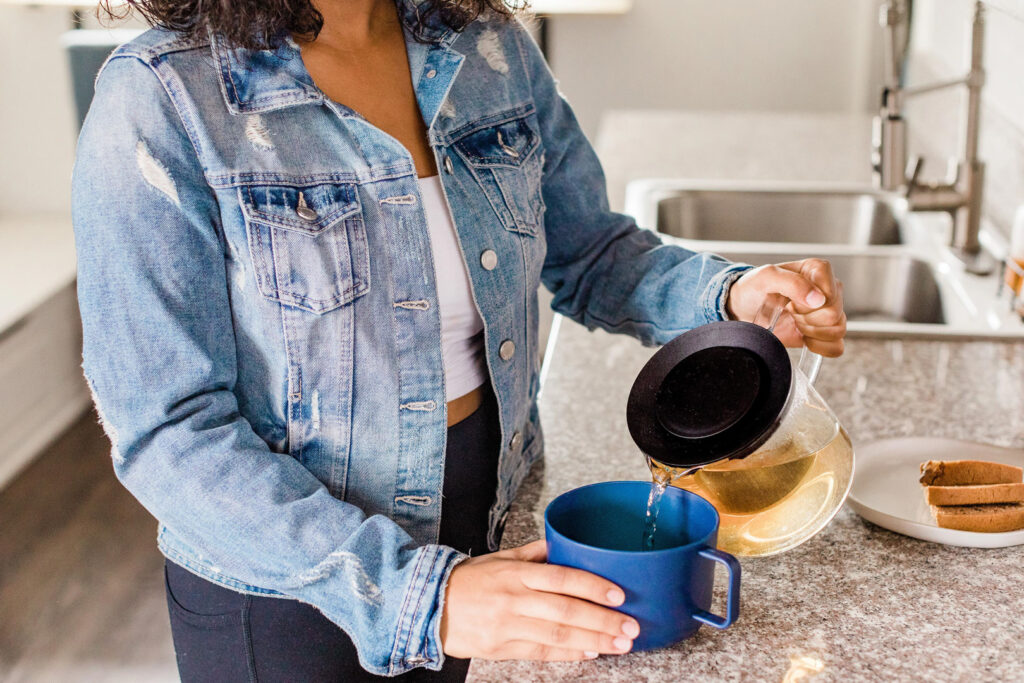 Person pouring tea into a blue cup.