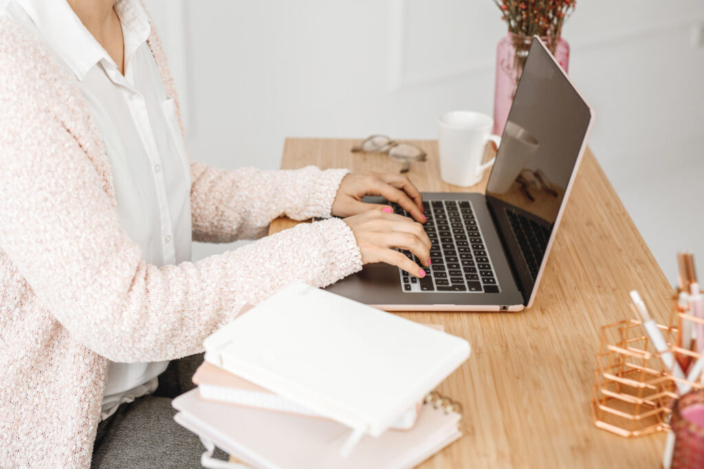 Person typing on laptop at wooden desk.