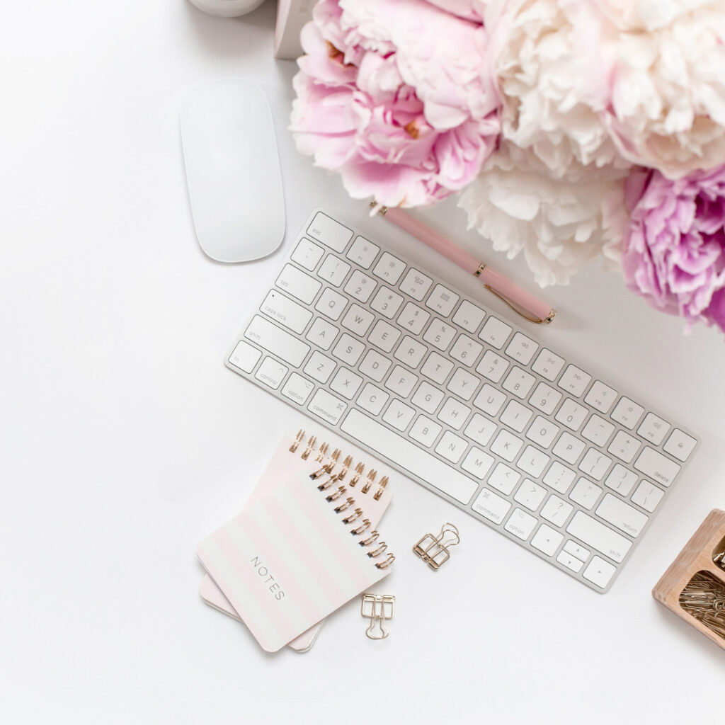 Desk with keyboard, flowers, notes, and mouse.