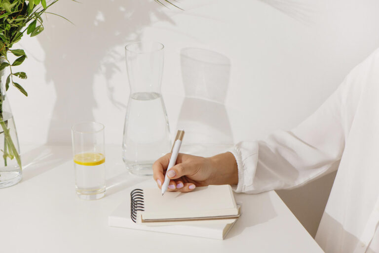 Person writing in notebook with lemon water.