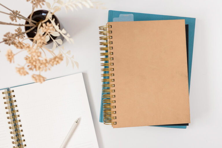 Notebooks and pen on white desk.