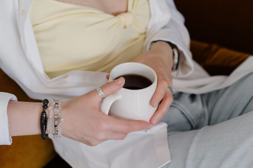 Person holding a coffee mug wearing bracelets.