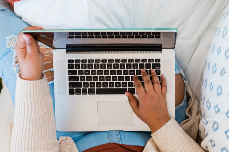 Person typing on laptop in cozy setting.