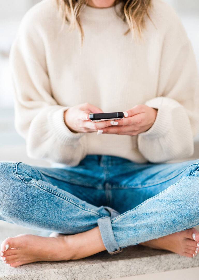 Person sitting cross-legged using smartphone indoors