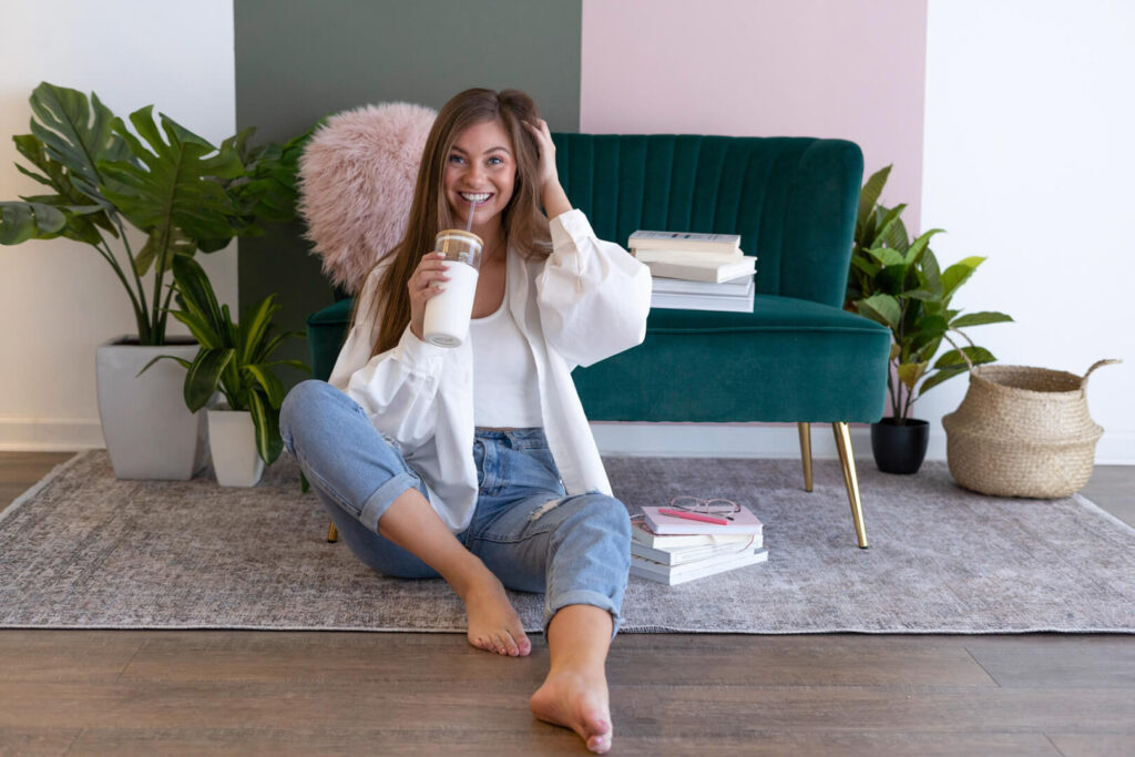 Smiling woman sitting on floor with drink
