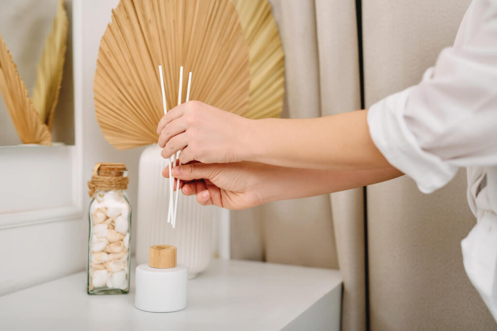 Hands arranging diffuser reeds on table
