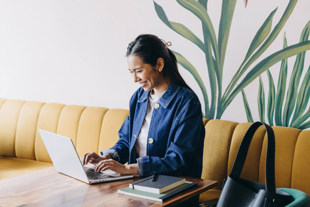 Woman smiling while working on laptop in cafe