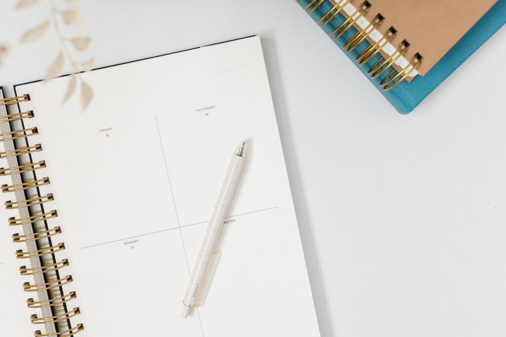 Open planner with pen on white desk