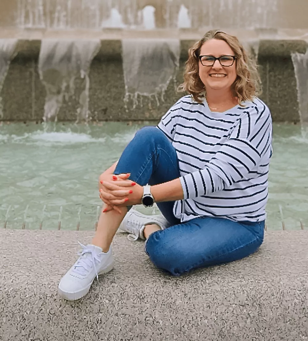 Woman sitting by fountain smiling at camera