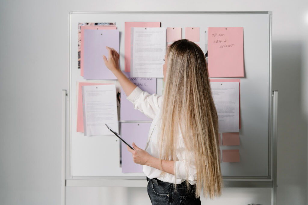 Woman organizing notes on office whiteboard