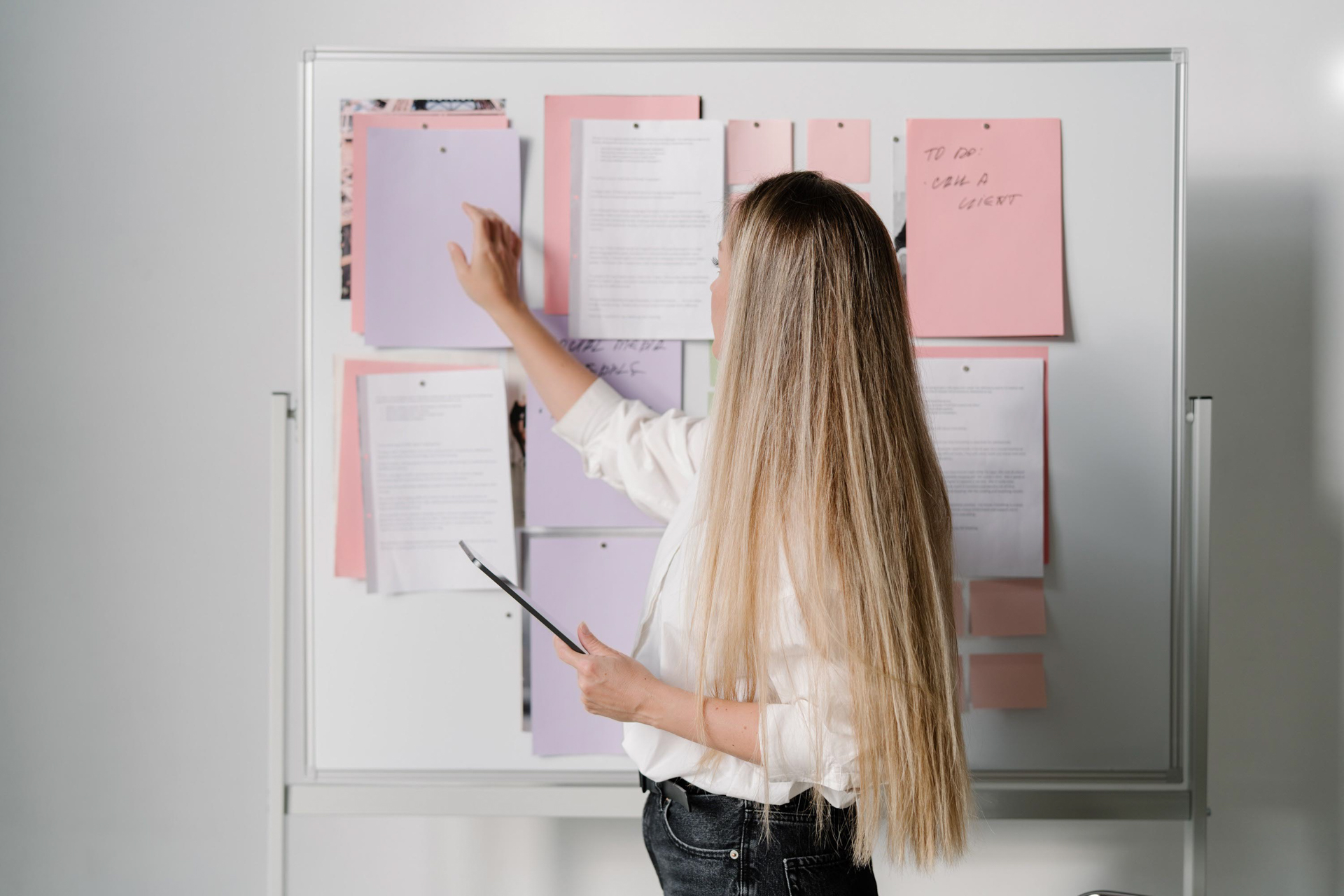 Woman organizing notes on office whiteboard