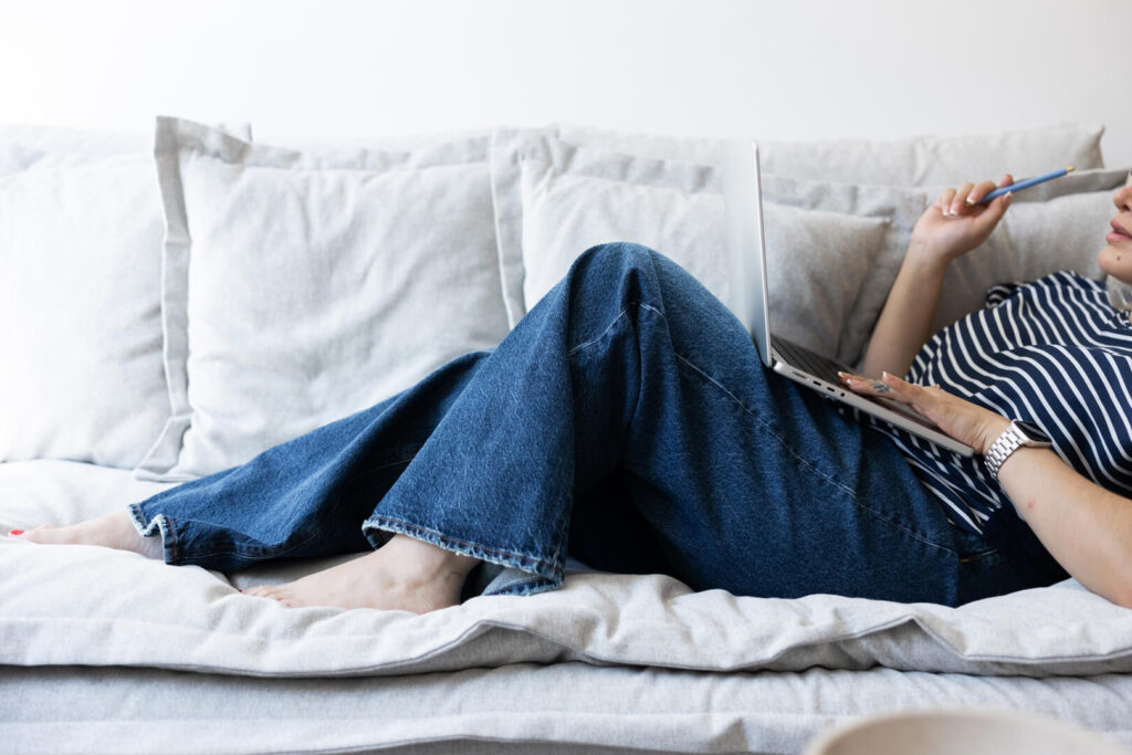 Person relaxing on couch using laptop