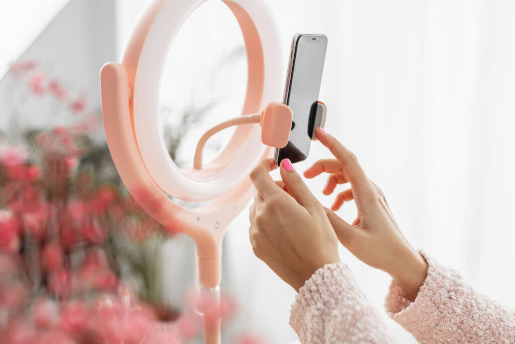 Person adjusting smartphone on pink ring light