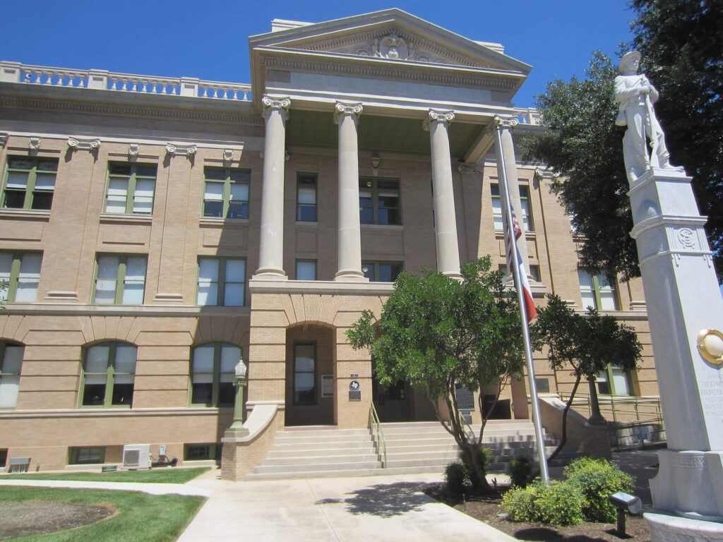 Neoclassical courthouse with columns, American flag, and soldier monument