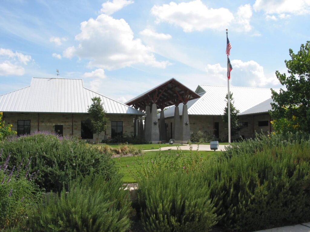 Stone civic building with flags and landscaped garden